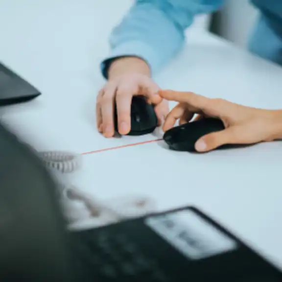 Zwei Hände, die eine Computermaus halten, berühren sich