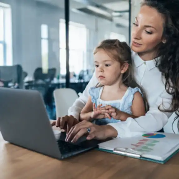 Frau am Laptop mit Tochter auf dem Schoß